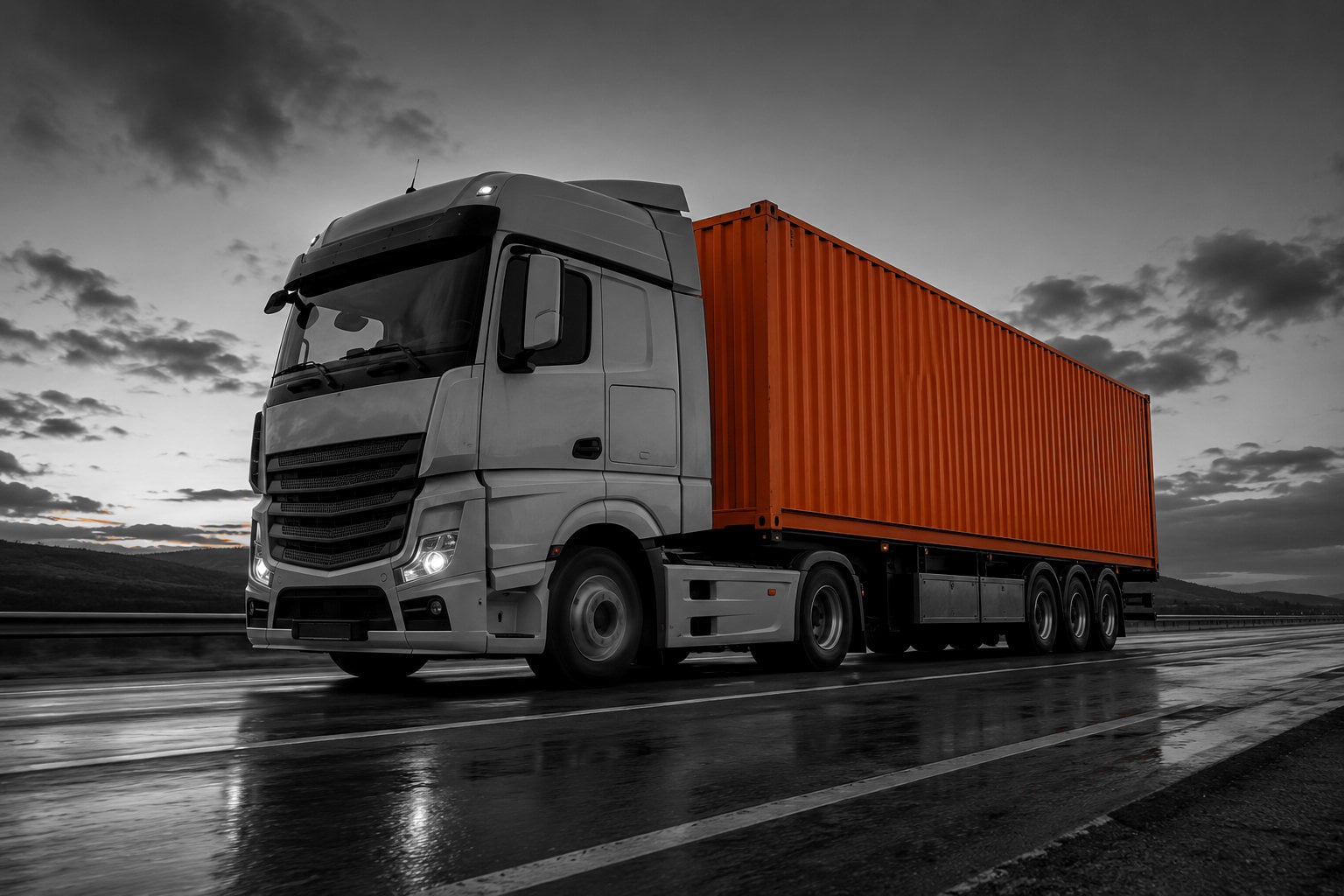 An articulated truck carrying a forty foot container on an open road at dusk.